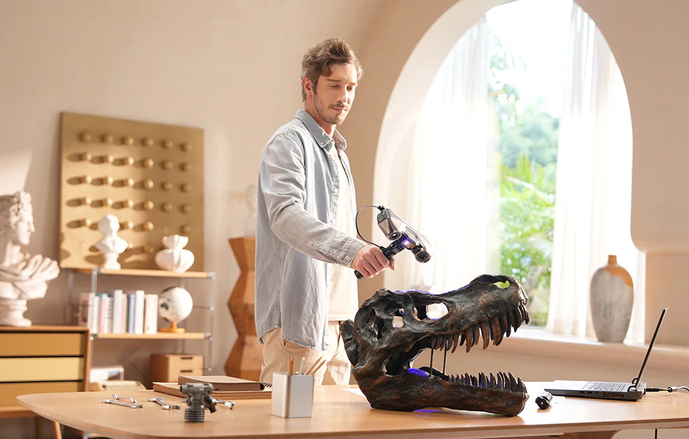 Un bărbat scanează o replică a unui craniu de dinozaur cu un scaner 3D într-o cameră luminoasă