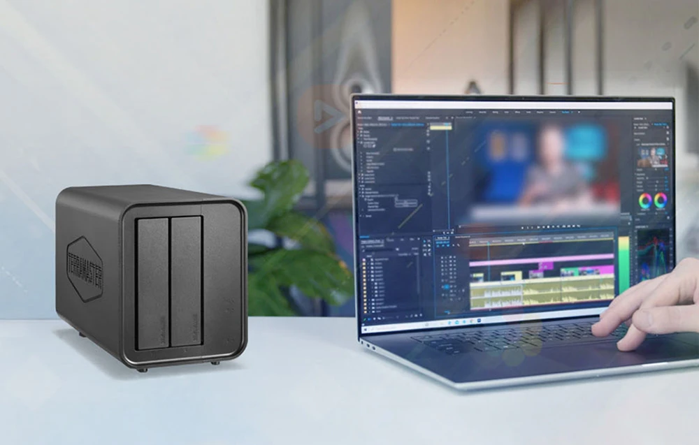 O carcasă pentru două unități de stocare lângă un laptop cu un program de editare video deschis