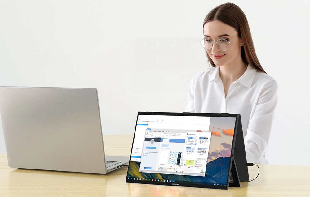 O femeie lucrează la laptopul ei, folosind monitorul pliabil ZEUSLAP ca ecran suplimentar