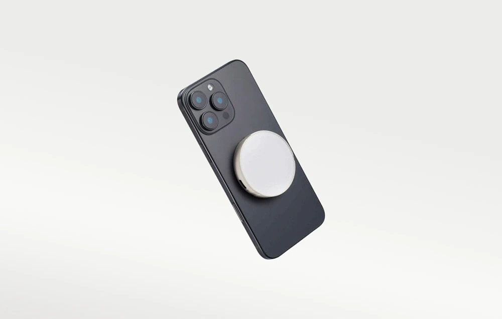 Un smartphone negru poziționat înclinat, cu o lampă LED Godox rotundă, albă, atașată magnetic