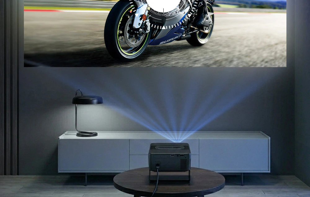 Proiectorul, așezat pe o măsuță de cafea, proiectează imaginea unei motociclete pe un ecran mare într-un interior modern.