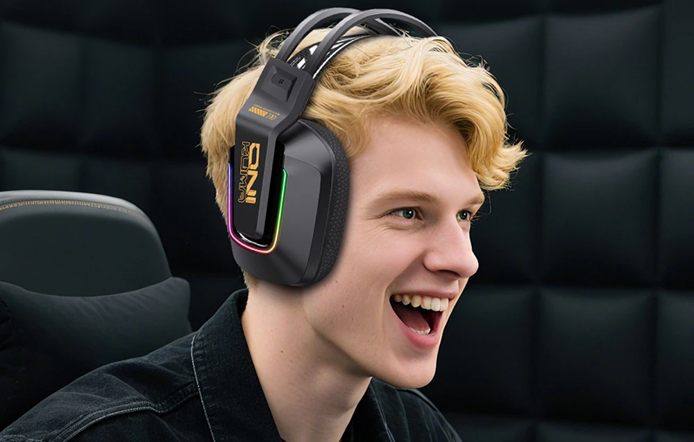 Tânăr zâmbitor cu păr blond purtând căști de gaming negre cu retroiluminare RGB