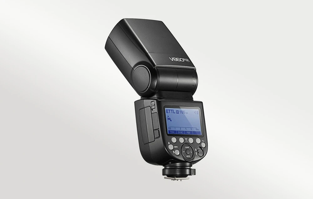 Blițul Godox V860III văzut dintr-un unghi, prezentând panoul de control, ecranul și capul înclinat
