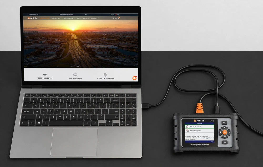 Scanerul de diagnosticare ANCEL MT300 conectat printr-un cablu USB la un laptop deschis, așezat pe un birou negru