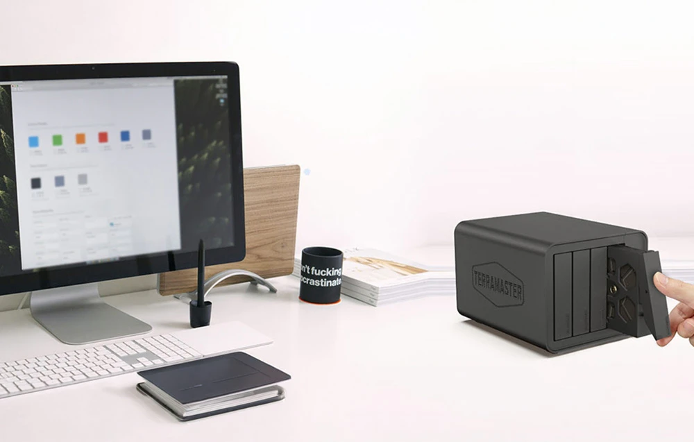 Carcasă pentru hard disk cu patru compartimente așezată lângă un computer desktop, cu o tăviță pentru unitate extensibilă