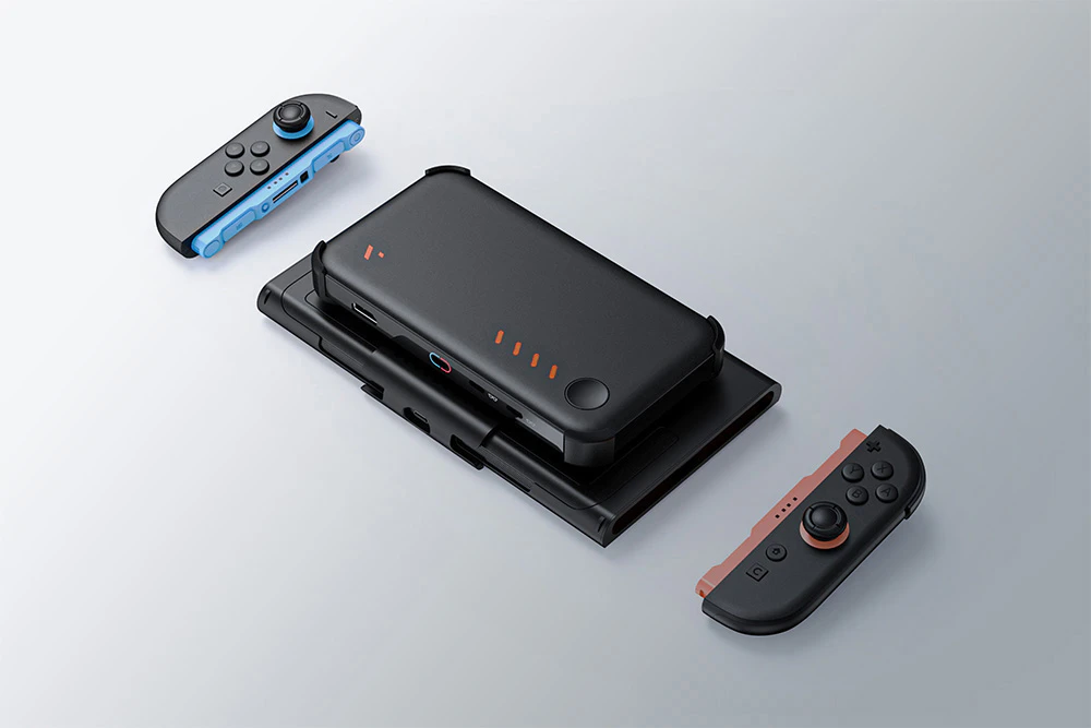Suport negru cu powerbank atașat și controllere pentru consolă detașate plutește deasupra unei suprafețe luminoase