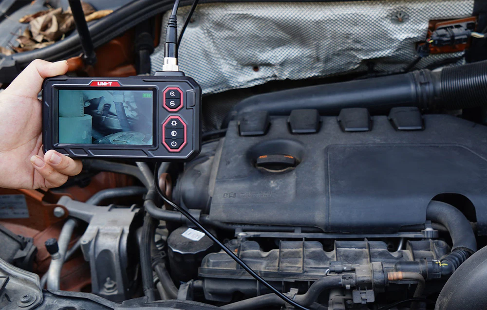 Boroscop video portabil utilizat pentru inspectarea componentelor motorului auto cu previzualizare a imaginii pe ecran.