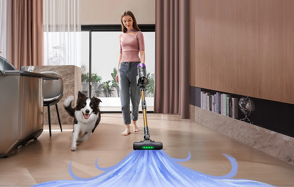 O femeie aspiră podeaua din sufragerie cu un aspirator vertical Ultenic; un Border Collie aleargă alături de ea
