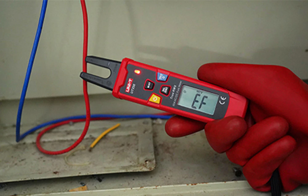Test de tensiune fără contact (NCV) cu un tester UNI-T efectuat în timp ce se poartă o mănușă de protecție roșie.