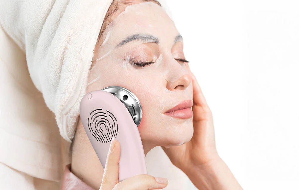 Femeia cu mască facială și prosop de păr folosește masorul facial