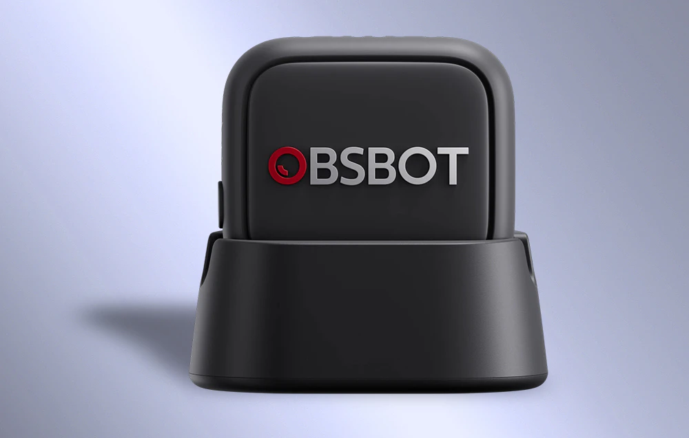 Microfon OBSBOT într-o carcasă neagră așezată pe o bază de încărcare cu un logo vizibil pe panoul frontal