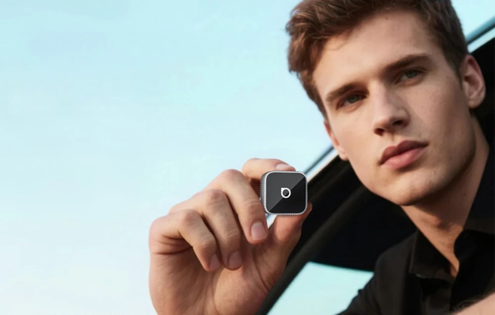 Un bărbat ținând în mână un adaptor auto mic pe un fundal albastru