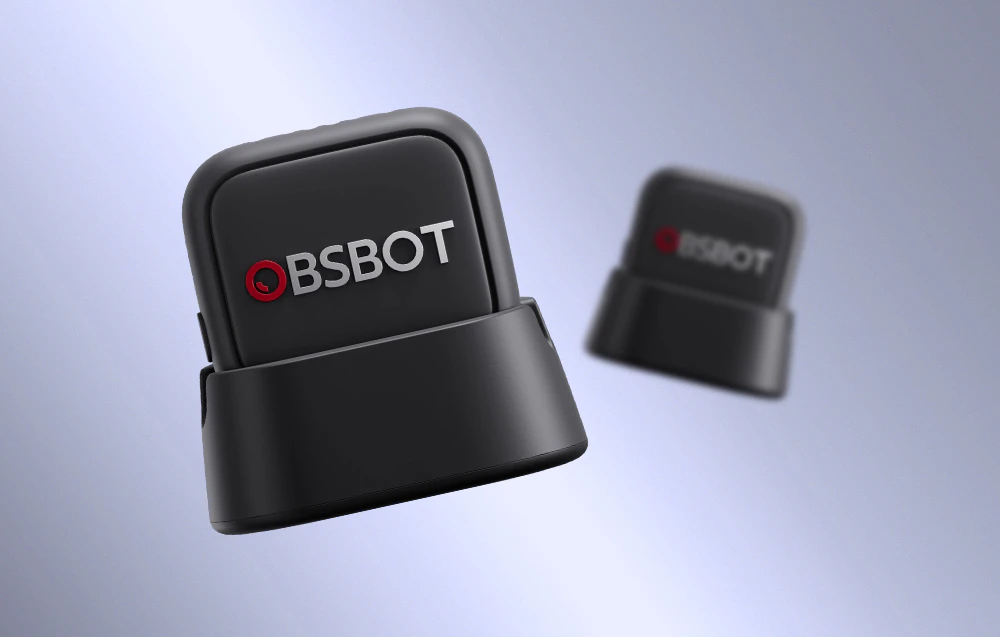 Două microfoane OBSBOT pe suporturi de încărcare capturate într-o perspectivă dinamică, unul în prim-plan cu focalizare clară și celălalt estompat în fundal
