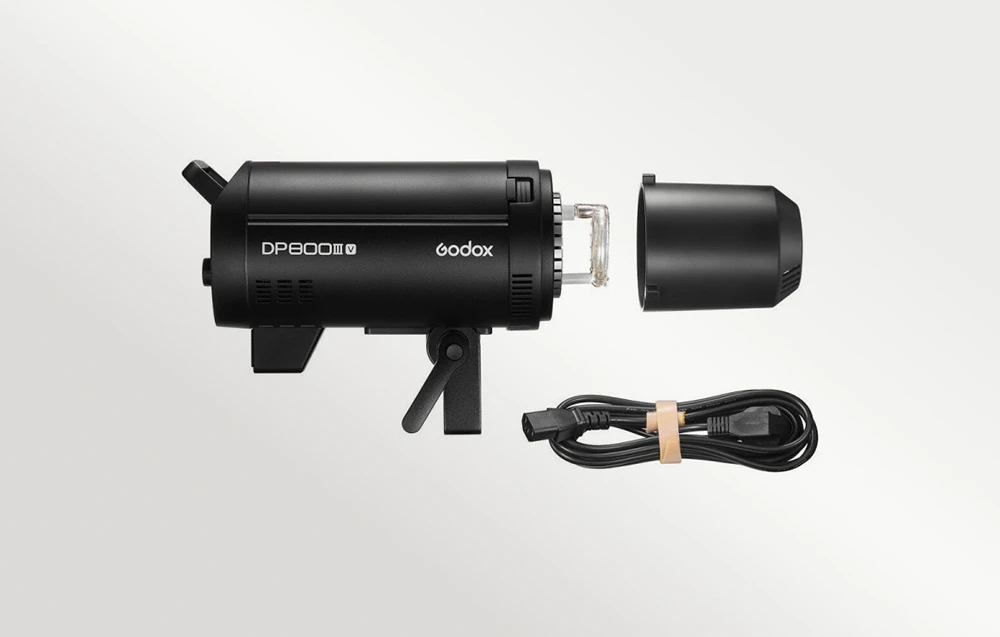 Unitatea de bliț Godox DP800III-V văzută din lateral, cu capacul capului de bliț îndepărtat și un cablu de alimentare negru în spirală lângă acesta