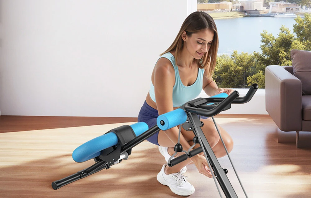 O femeie în ținută sportivă reglează setările unui aparat de exerciții abdominale negru și albastru într-o sală de fitness.