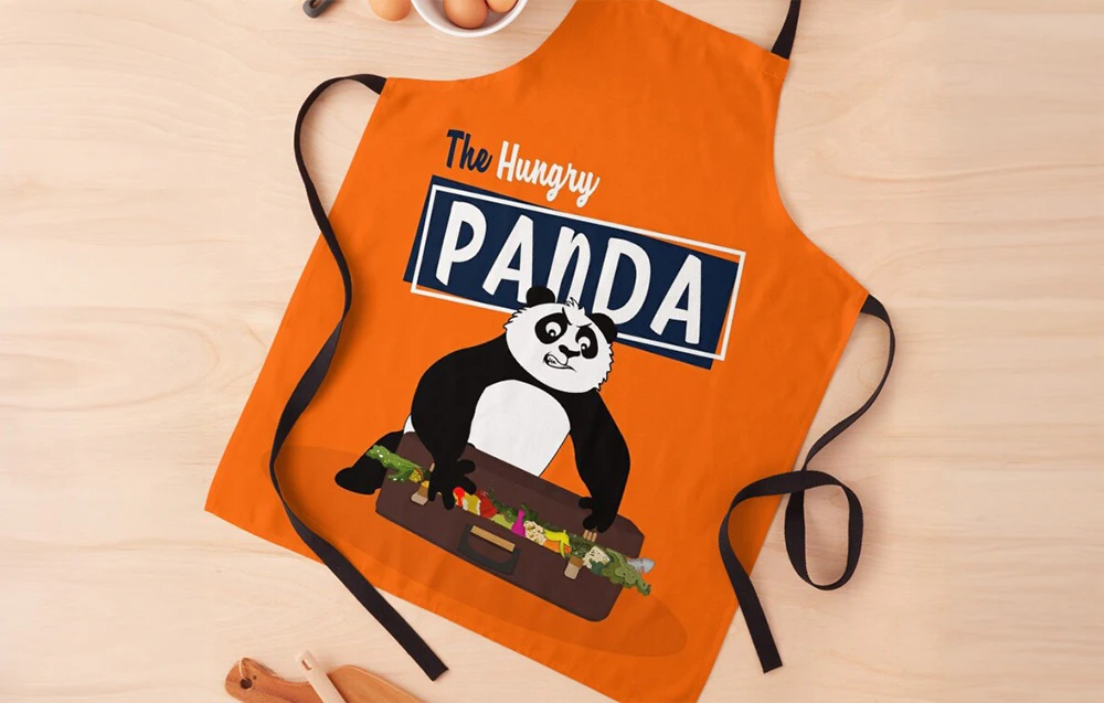 Șorț de bucătărie portocaliu cu un panda care poartă o valiză plină de mâncare și textul „The Hungry Panda”.
