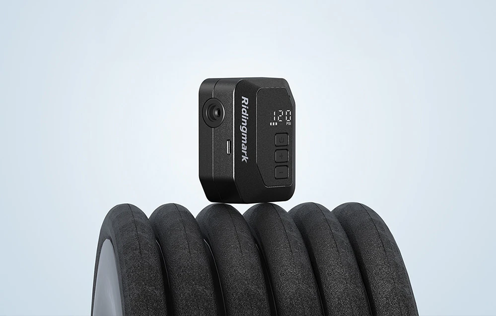 Pompa electrică AS280PRO neagră, cu afișaj de 120 PSI, așezată pe o cameră de bicicletă rulată