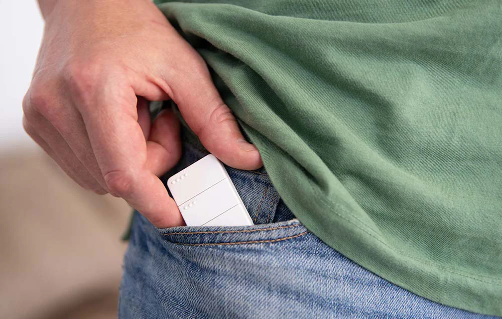 Telecomandă mică albă scoasă din buzunarul blugilor