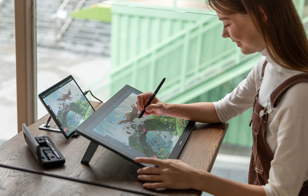 Femeie desenând pe tableta Huion cu monitor suplimentar care arată lucrarea