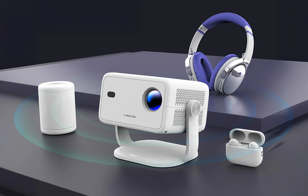 Un proiector alb lângă un difuzor wireless, căști și o husă cu căști TWS