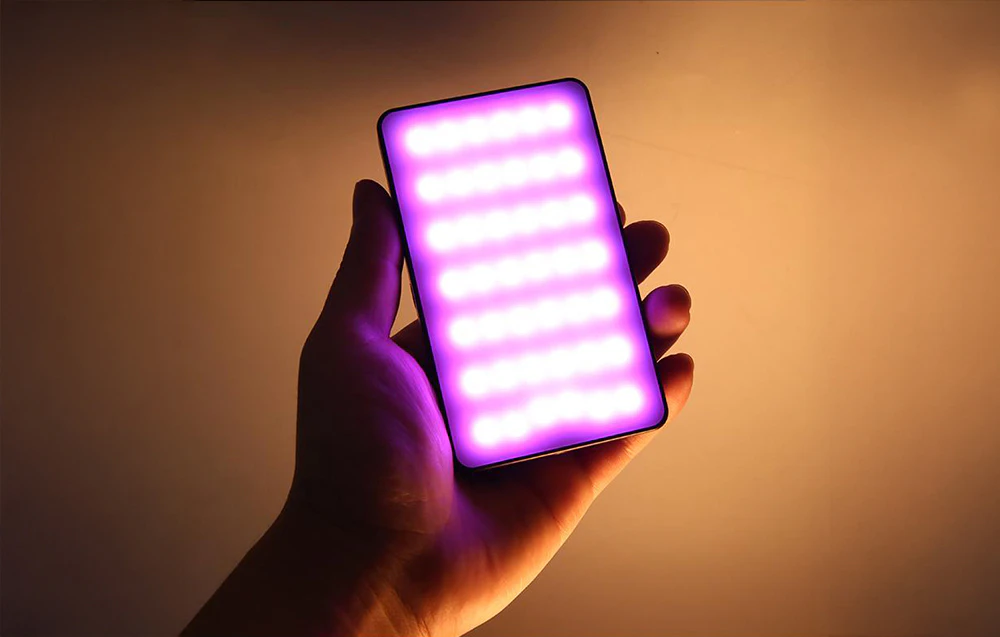 Lampa compactă RGB PULUZ LED ținută în mână strălucește cu lumină violet și portocalie care prezintă efecte de culoare