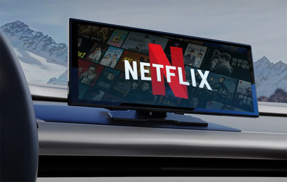 Un ecran de mașină cu logo-ul Netflix pe fundalul unor munți înzăpeziți, montat pe tabloul de bord