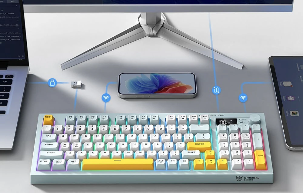 Tastatură în culori pastelate pe un birou cu laptop, smartphone și monitor