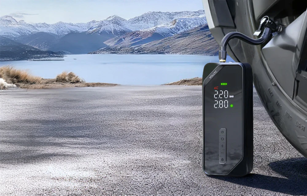 Compresorul wireless Vollyc umflă un pneu de mașină pe fundalul unor munți pitorești acoperiți de zăpadă și al unui lac