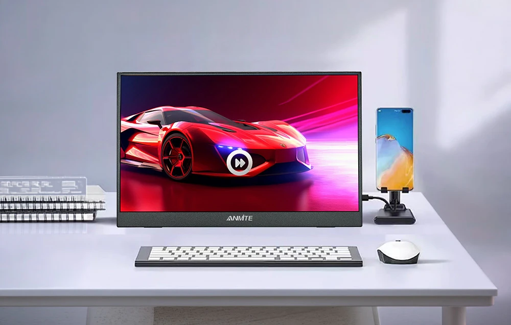O stație de lucru cu un monitor pe care este afișată o mașină roșie, o tastatură, un mouse și un telefon.