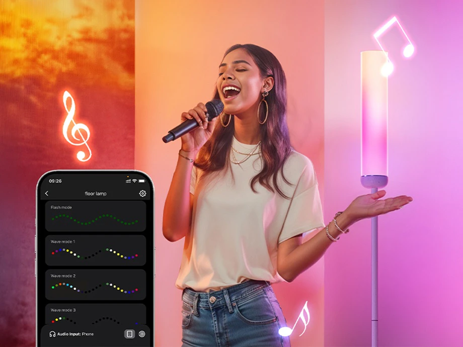 O femeie cântând la un microfon, având ca fundal un smartphone cu o aplicație de muzică și o lampă care strălucește cu lumină roz.