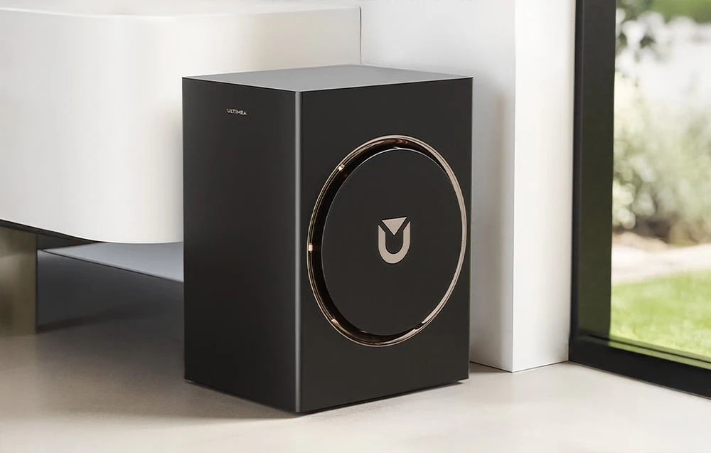 Subwoofer negru așezat pe o podea albă lângă o fereastră