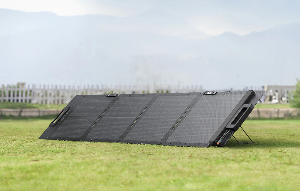 Panou fotovoltaic pe iarbă verde, cu gardul proprietății în fundal