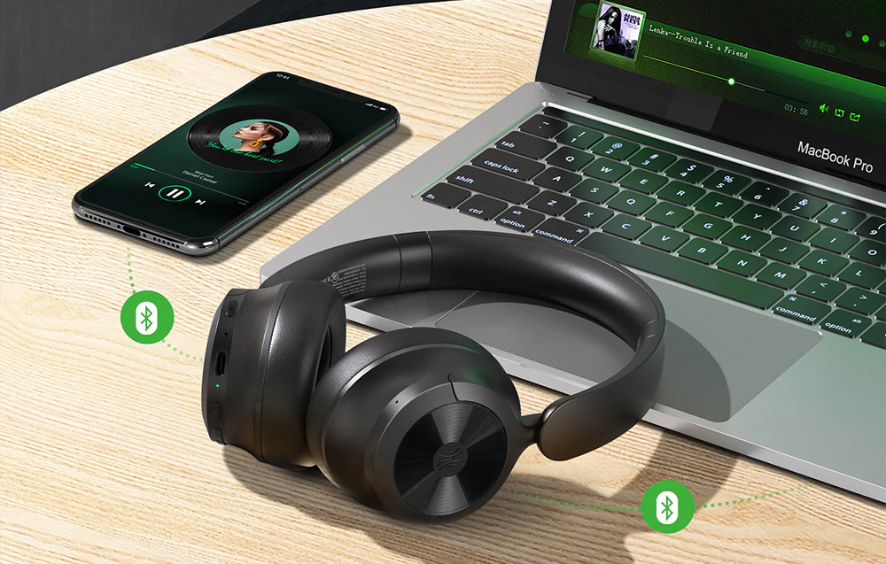 Căști fără fir pe un birou lângă un laptop și un smartphone cu pictograme de conexiune Bluetooth