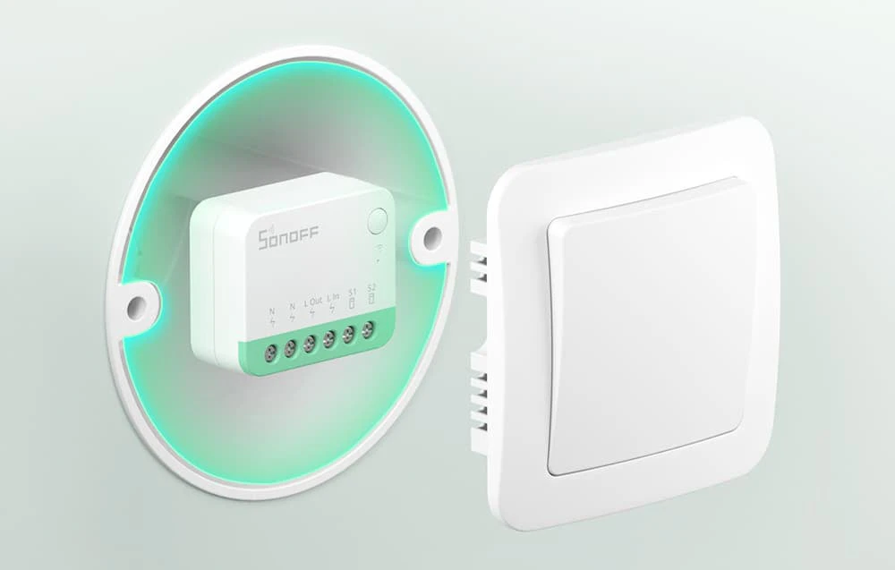 Modul Sonoff Mini Extreme montat într-o cutie de instalare cu un capac vizibil sub forma unui comutator