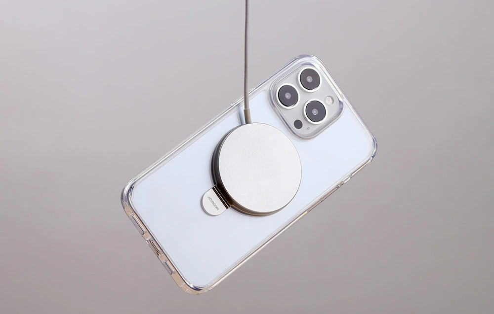 Smartphone cu carcasă transparentă cu element magnetic, conectat prin cablu.