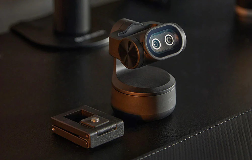 Camera web EMEET Pixy cu suport este așezată pe un birou negru