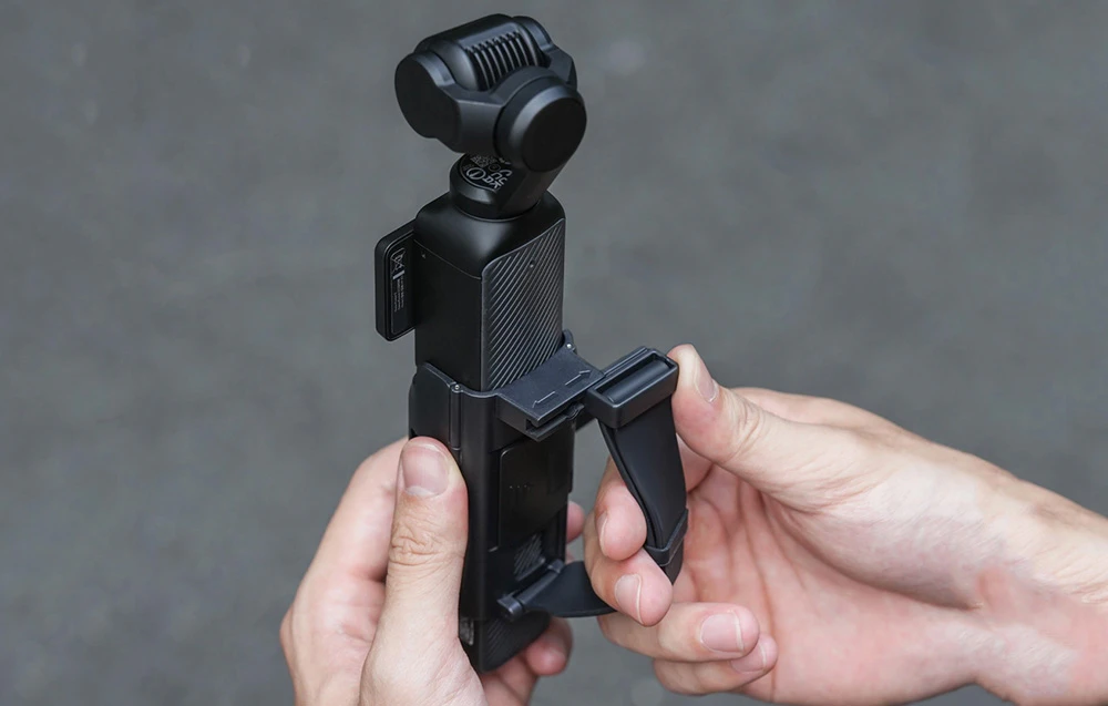 Două mâini care desfășoară un mâner montat pe o cameră mică cu gimbal