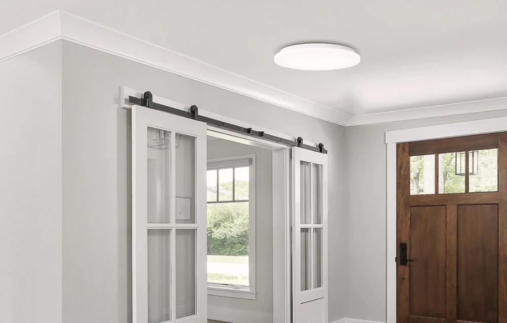 Lampă Yeelight MercuryE C260 montată într-un hol luminos cu uși glisante și o ușă de intrare din lemn.