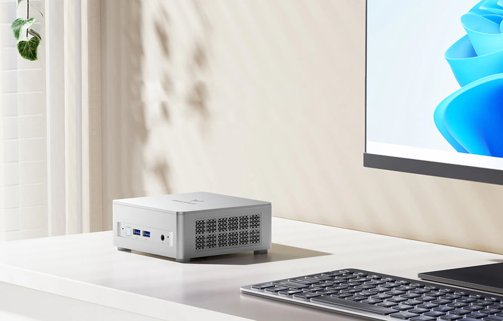 mini PC alb pe un birou lângă un monitor cu tastatură