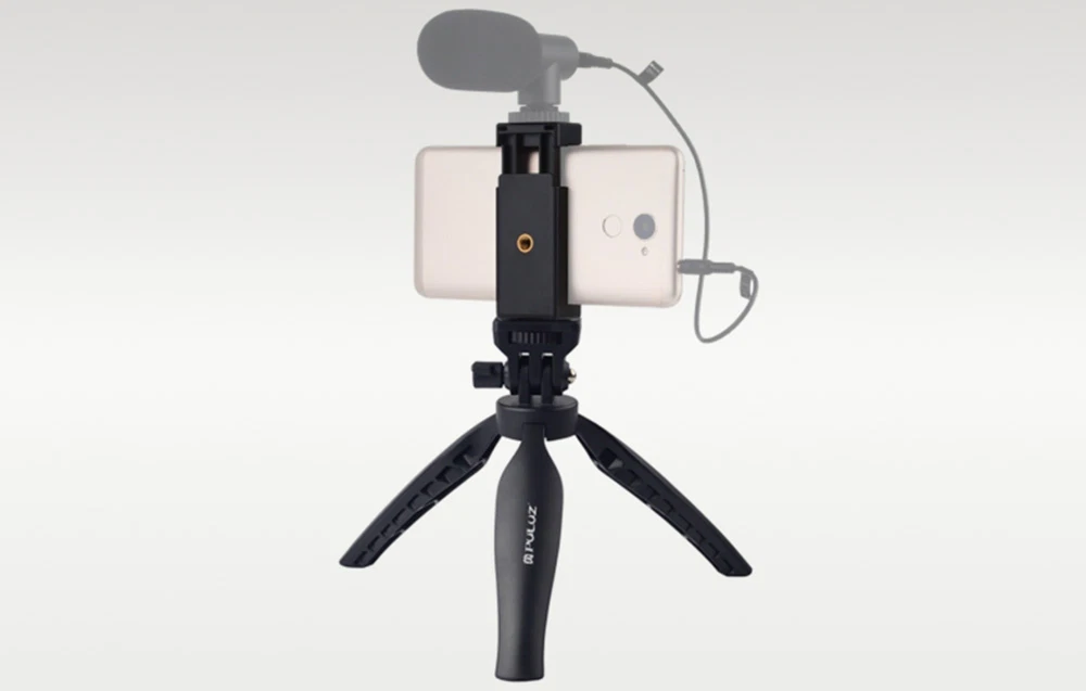 Un smartphone cu microfon montat în suportul de pe un mic trepied de birou negru.