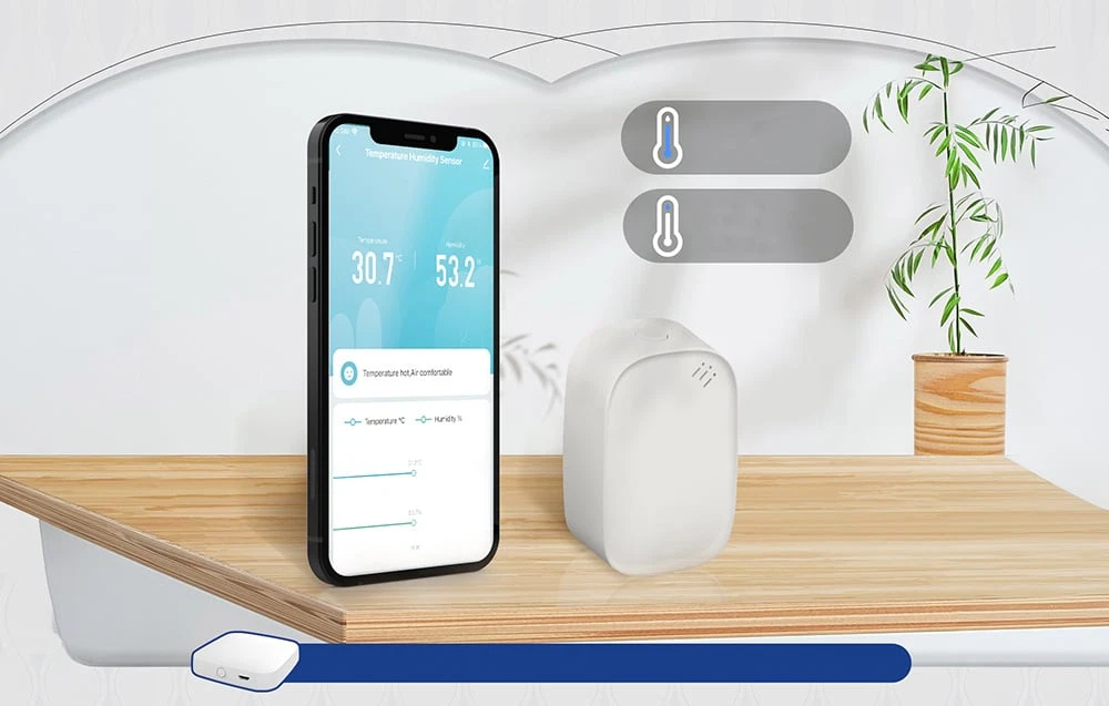 Smartphone-ul afișează o temperatură de 30,7 °C și o umiditate de 53,2% lângă senzorul alb așezat pe un blat de lemn