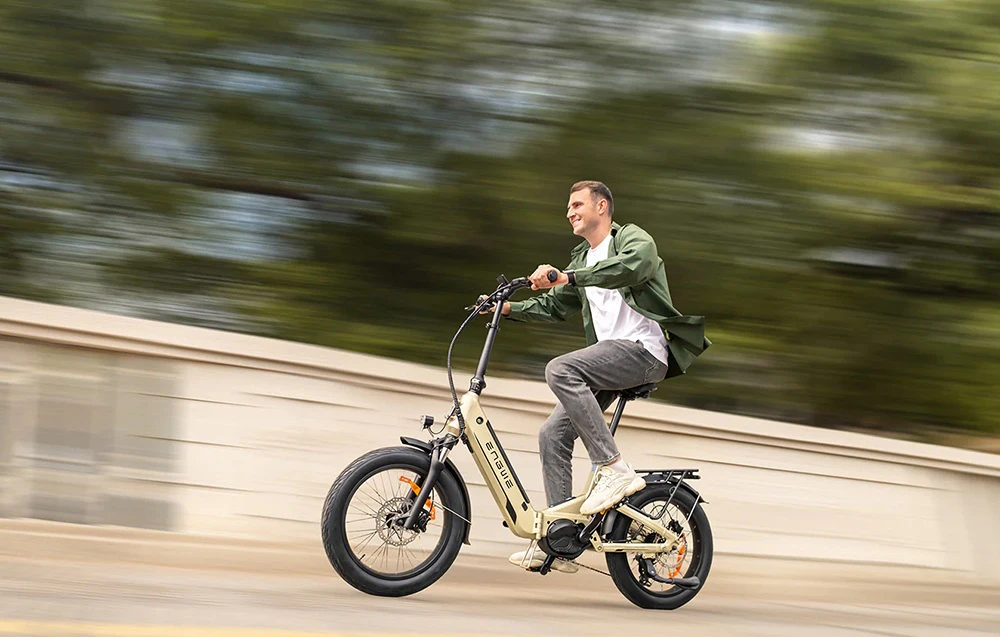 Un băiat care merge cu o bicicletă electrică neagră pe trotuarul unui oraș modern