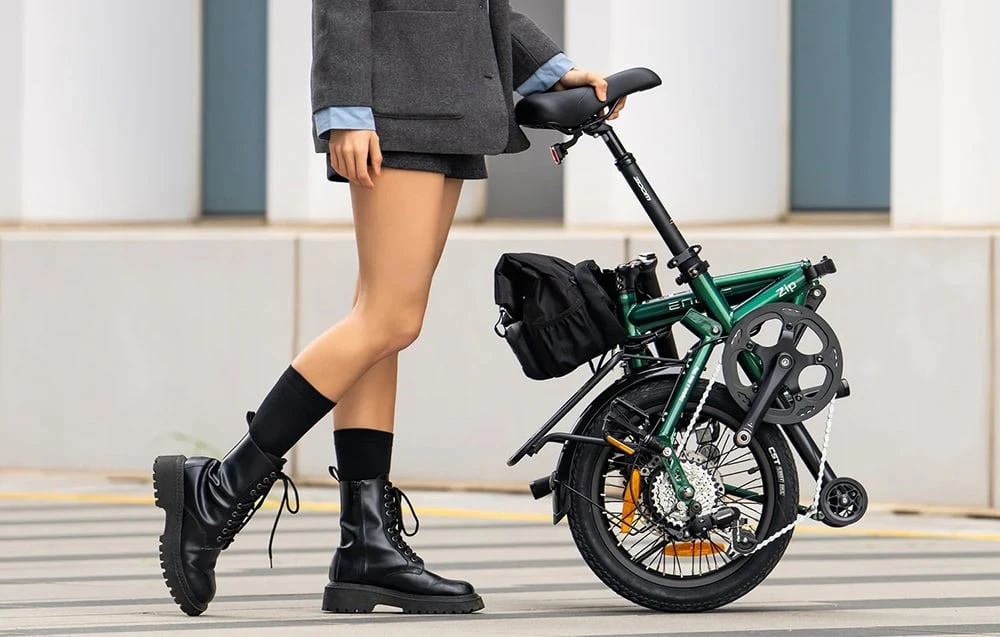 O femeie împinge o bicicletă electrică pliabilă, ținând-o de șa