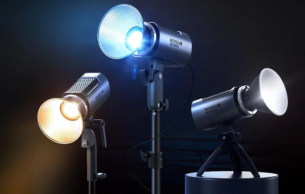 Trei lămpi de studio Neewer pe stative emițând lumină caldă, rece și neutră