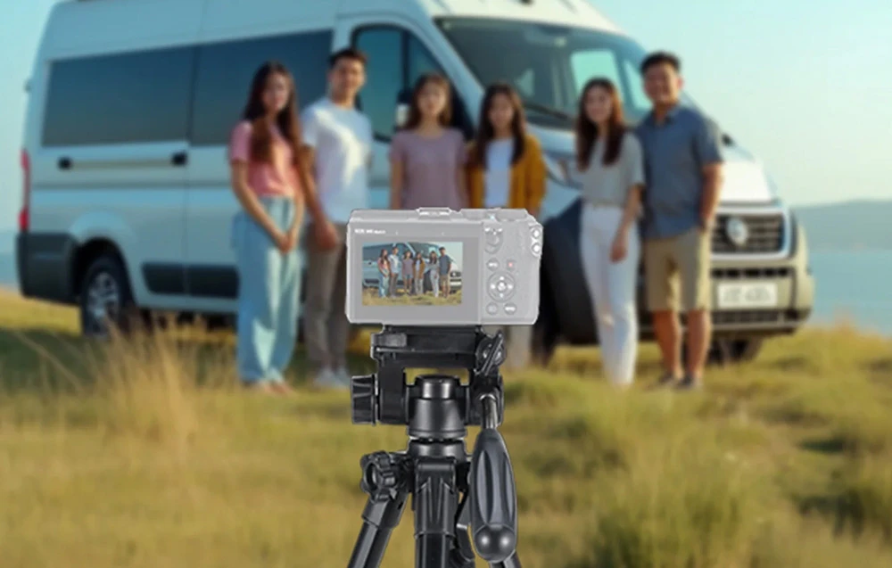 O cameră montată pe un trepied face o fotografie de grup cu șase persoane care stau în fața unei rulote