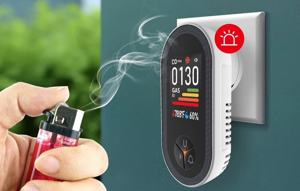 Brichetă care emite fum lângă senzorul conectat la o priză, cu „0130” și o pictogramă roșie de alarmă pe ecran