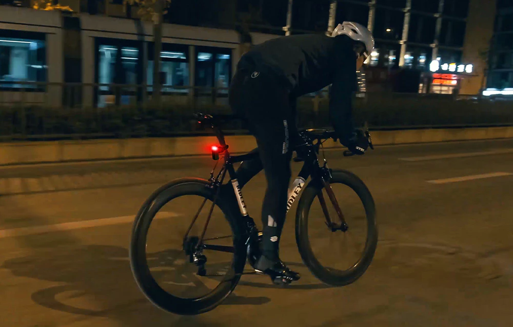 Ciclist care circulă noaptea în oraș cu o lumină roșie spate
