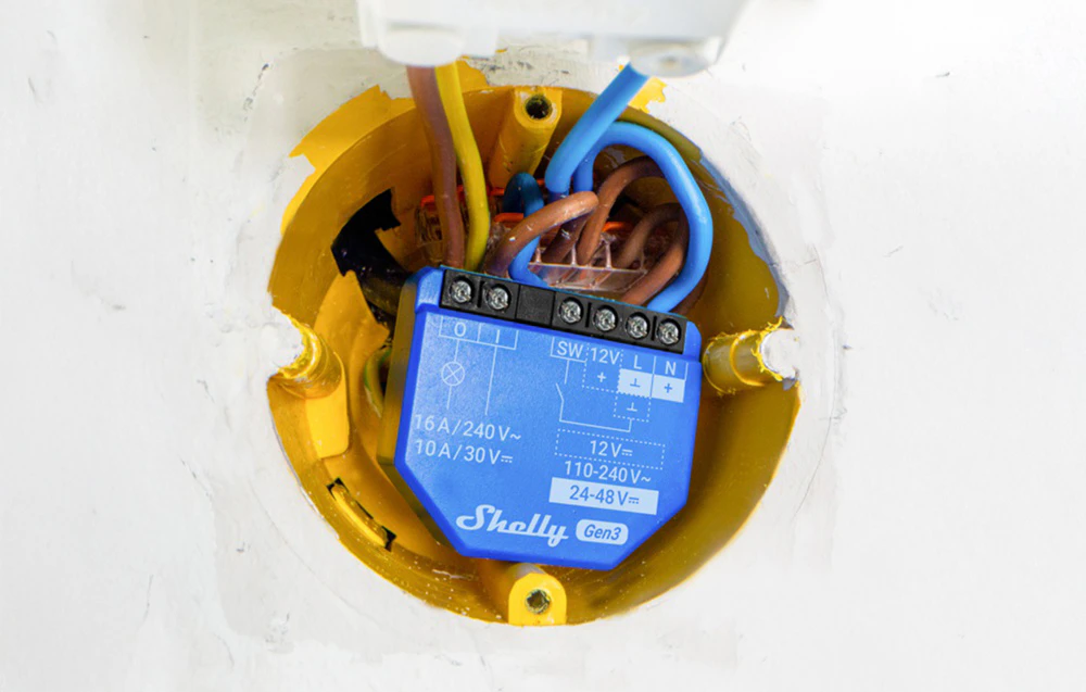 Modul Shelly Gen3 montat într-o cutie electrică cu firele conectate, încastrat în perete