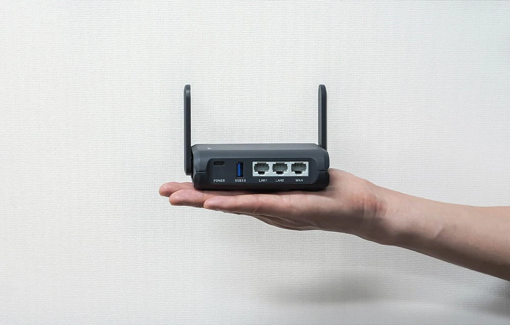 Router negru cu antene ținut în mână pe un fundal deschis