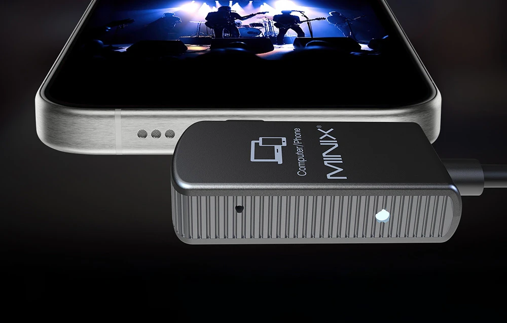 Adaptor MINIX conectat la un smartphone care afișează o înregistrare a unui concert pe un fundal întunecat